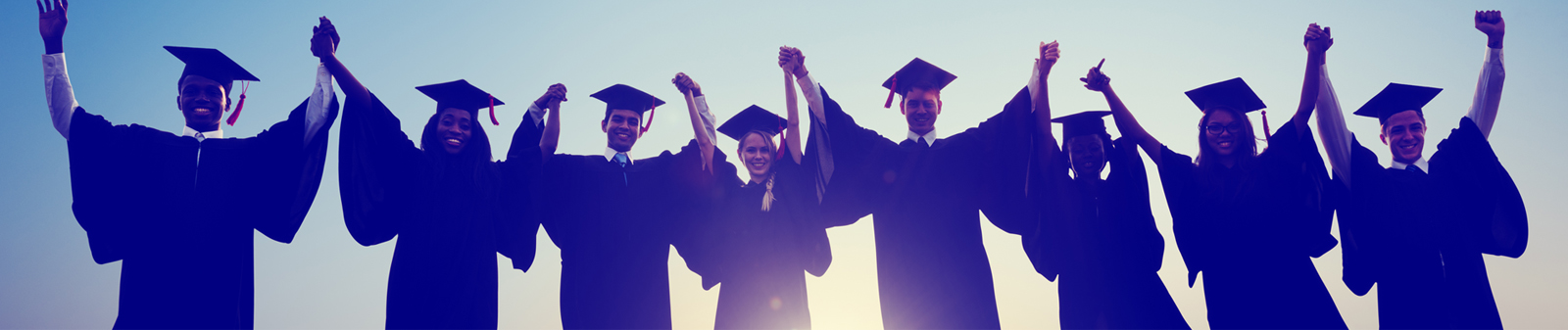 graduates in caps and gowns raising up arms with excitement