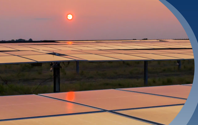intense red orange sun above the horizon reflecting warm colors across a field of solar panels in the foreground
